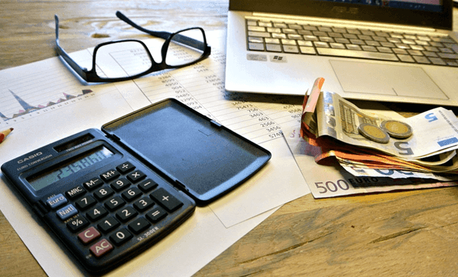 une calculatrice, des lunettes et des feuilles de calcul fiscal