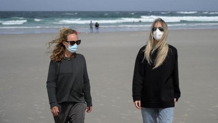 Avec un masque en promenade sur la plage