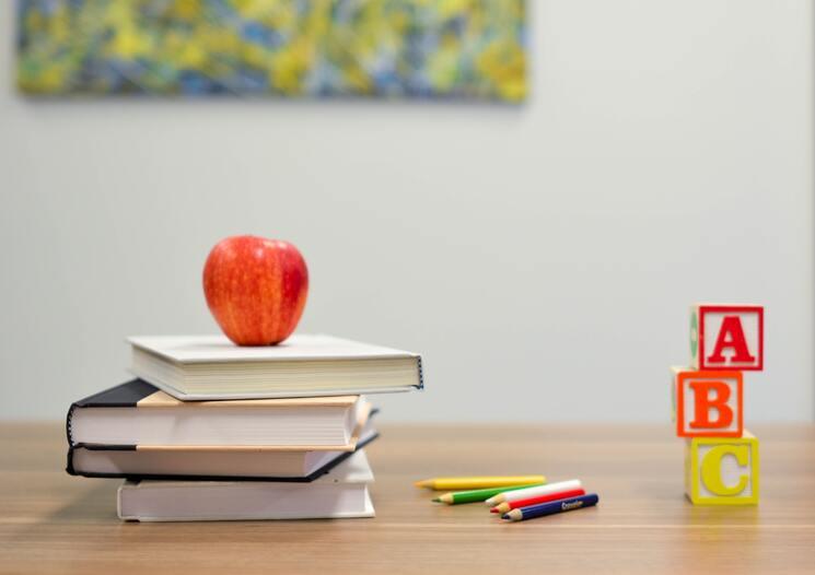 Une pomme est posée sur trois manuels scolaires