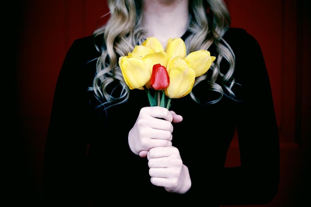 Une femme en tenue de deuil, un bouquet de fleurs à la main