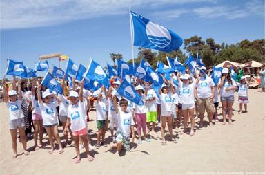 Des enfants tiennent des drapeaux bleus sur une plage en Andalousie