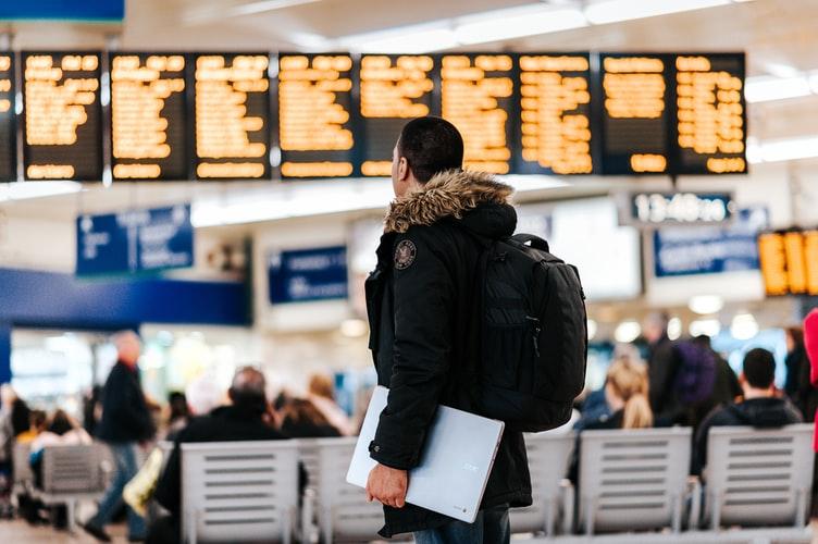 Un homme regardant des tableaux de départs dans un aéroport