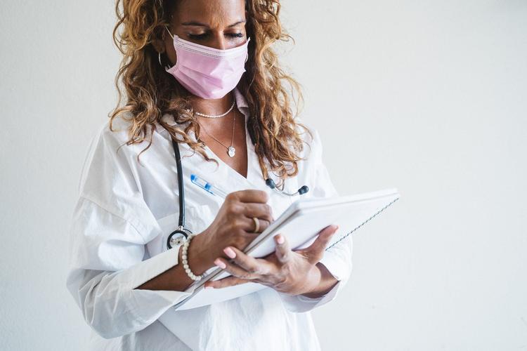 Une femme docteure prenant note sur un carnet 