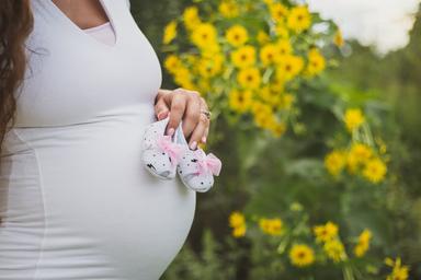 Une femme enceinte tenant des chaussons de naissance