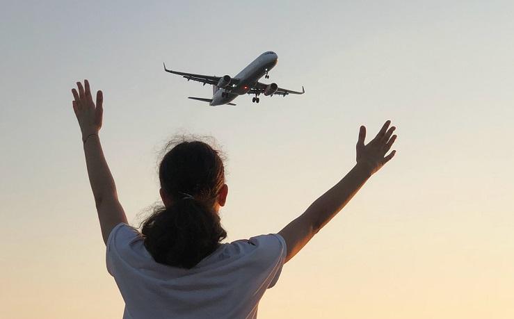 une personne salue un avion qui passe dans le ciel