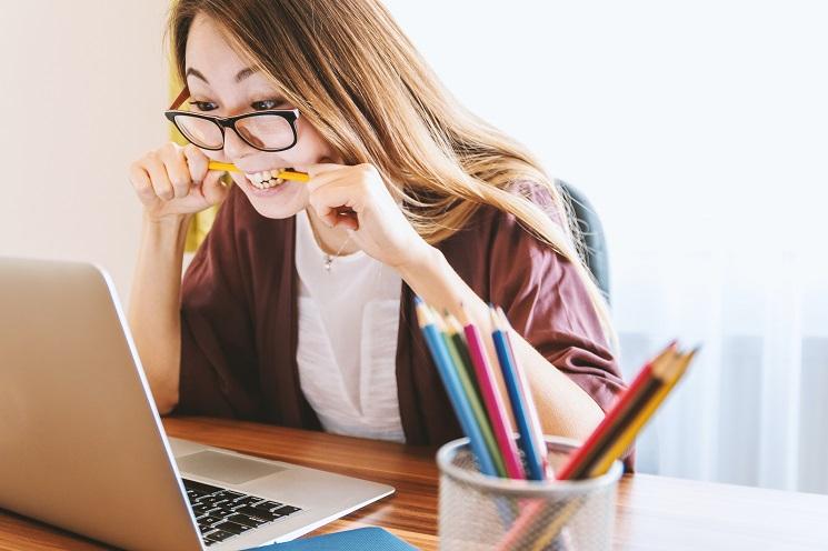 Une femme contrariée devant son ordinateur mordille violemment un crayon 