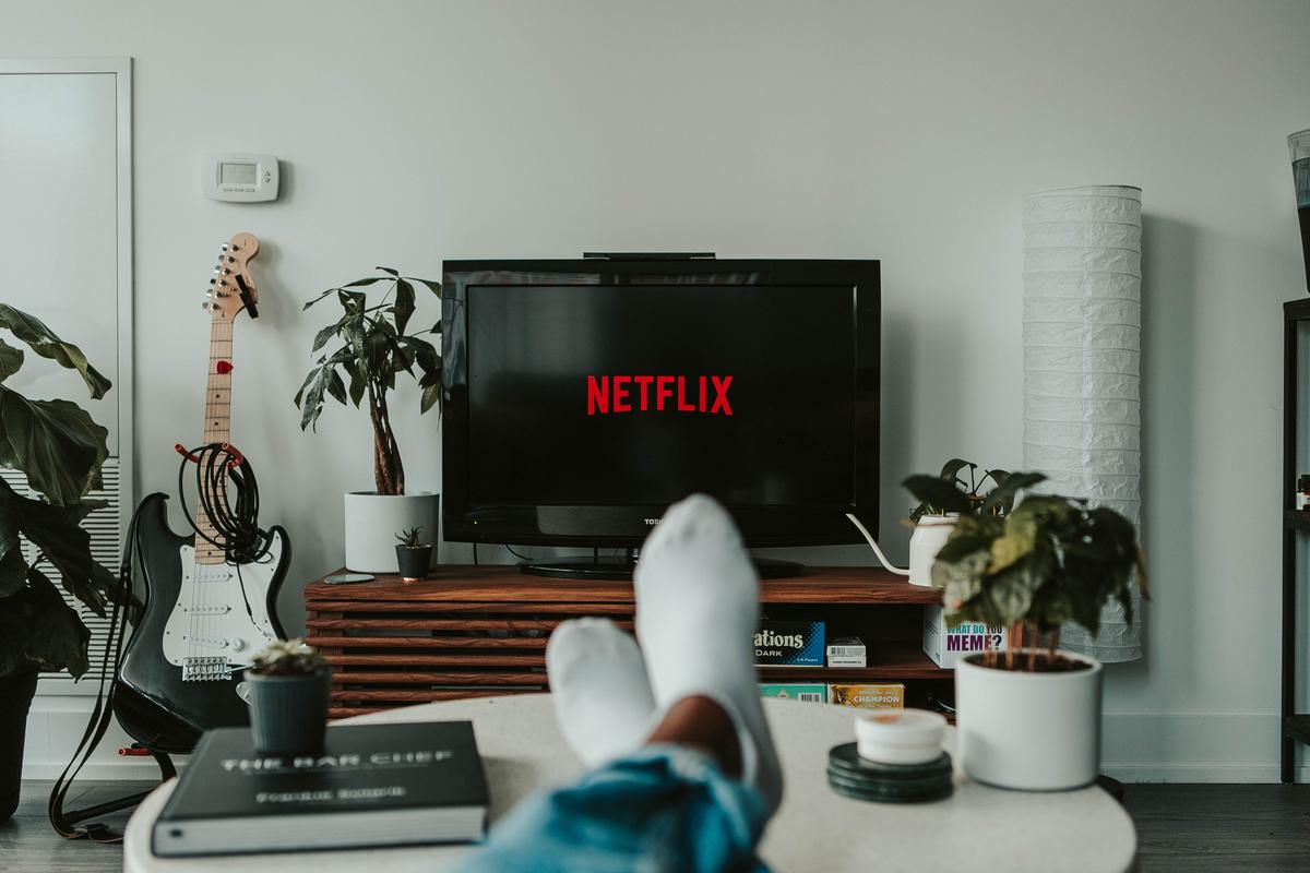 Une personne regarde la télévision, le logo de Netflix est affiché.