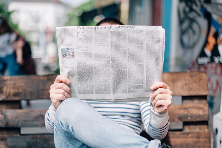 Une personne cachée derrière son journal