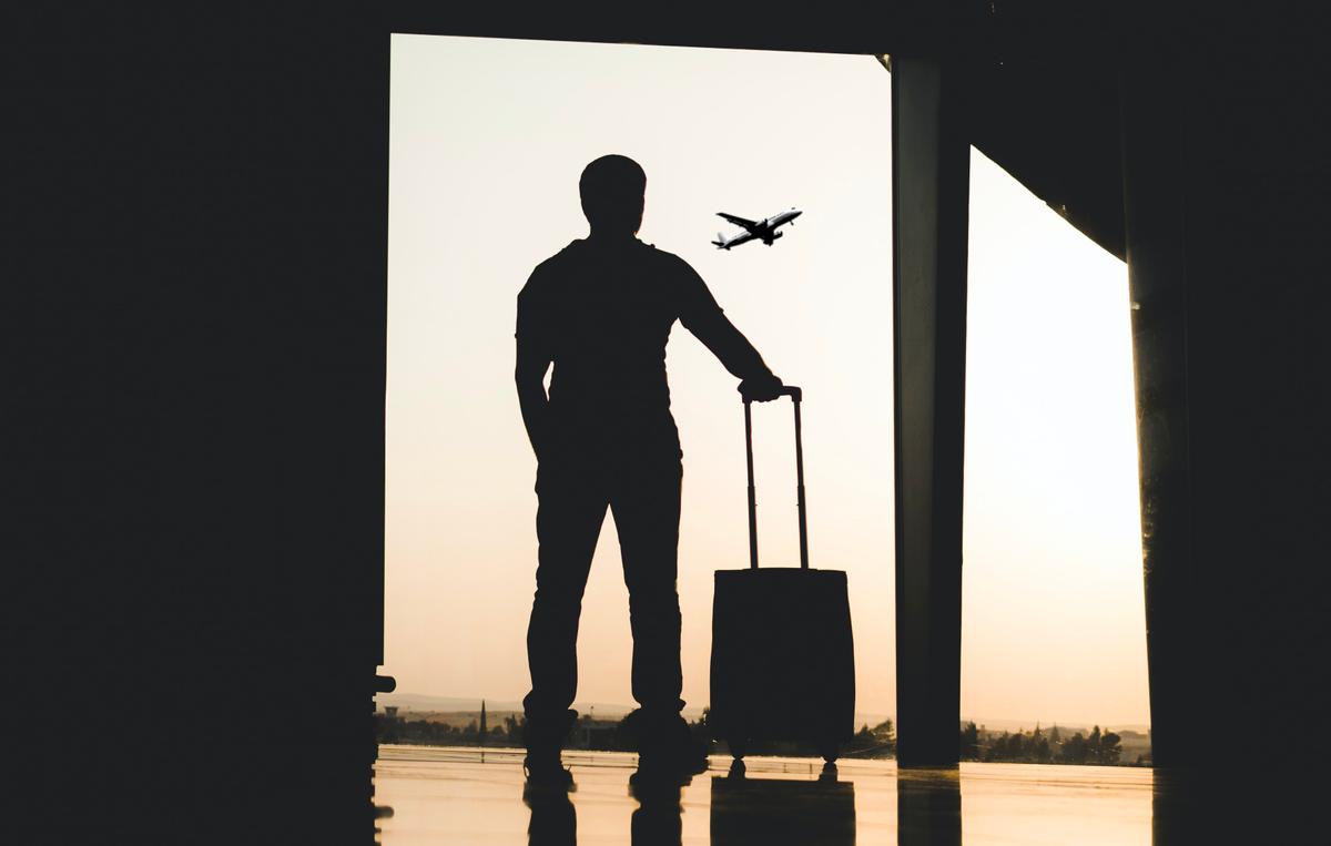 Un homme regarde à travers une fenêtre un avion s'envoler