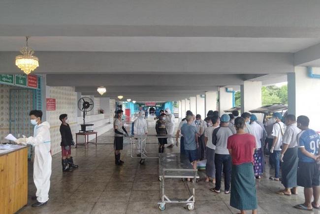 Des Birmans devant un des crématoriums du cimetière de Yayway, à Yangon