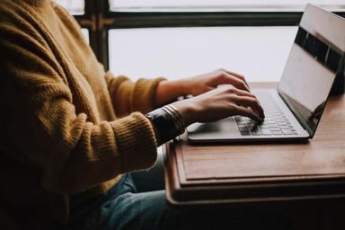 Une femme écrit sur son ordinateur