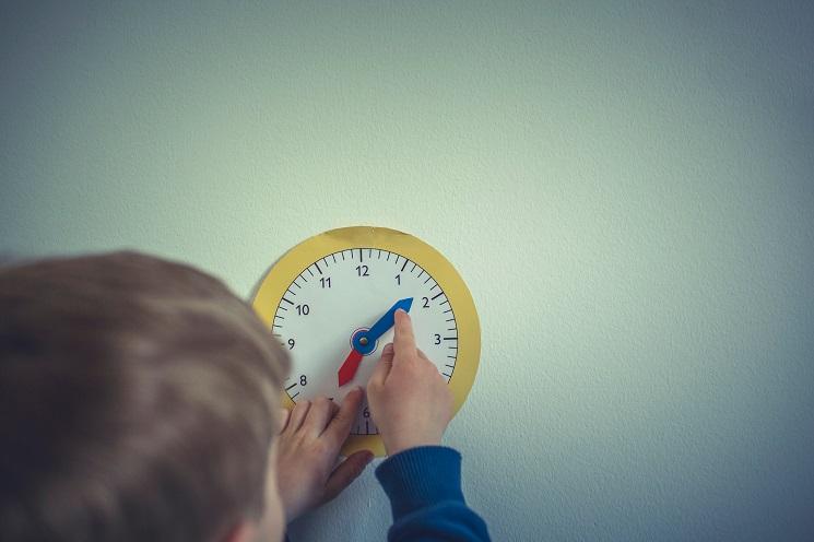 Un écolier réglant une horloge colorée pour enfants