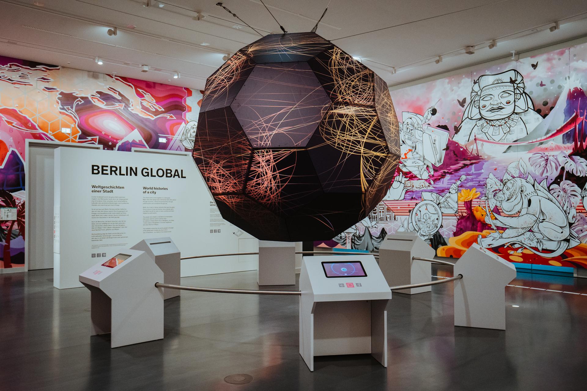 Un planisphère dans la première salle de l'exposition Global Berlin, avec un fresque un fond.