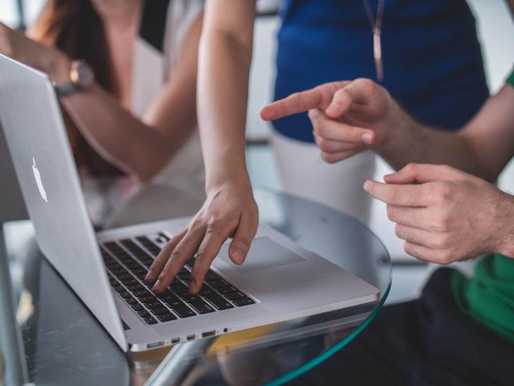 Une équipe au travail face à un ordinateur apple portable