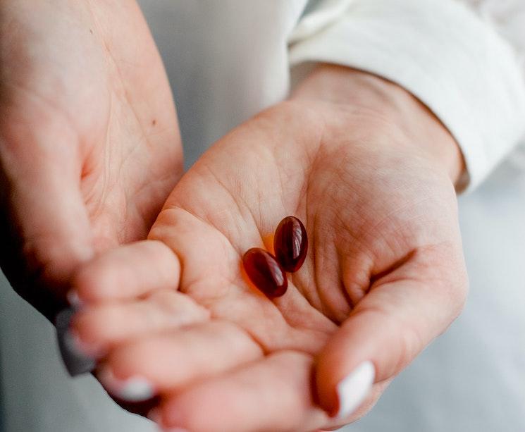 Une femme médecin tient dans ses mains deux gélules