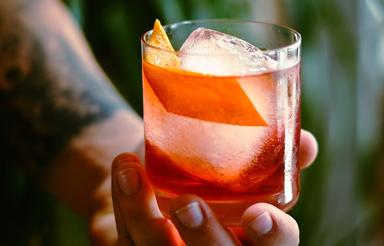 Un barman tatoué sert un joli cocktail Negroni