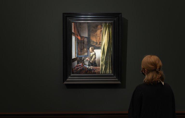 Une personne devant le tableau La Liseuse à la fenêtre de Vermeer dans l'exposition à la Gemaldegalerie de Dresde