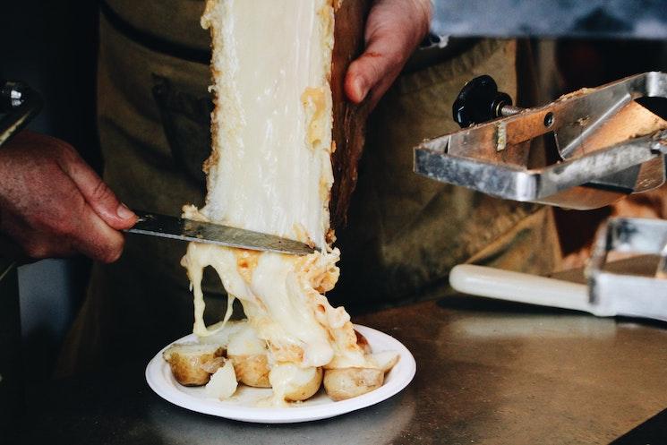 Un restaurateur est en train de servir de la raclette sur une assiette de pommes de terre