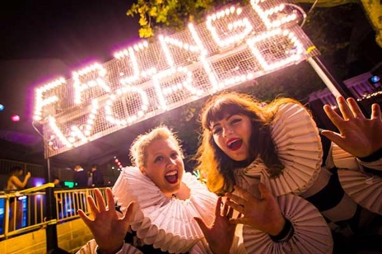 Deux femmes devant l'inscription lumineuse "Fringe World"