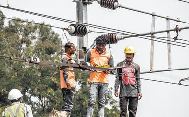 des ouvriers sur un pylône électrique en Inde