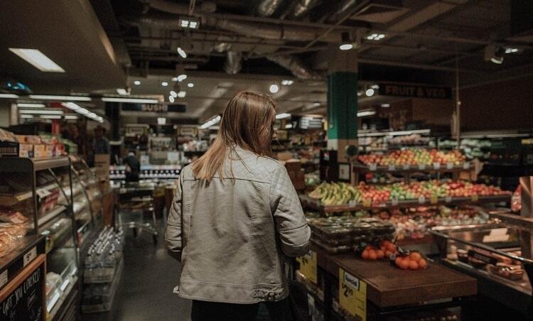 une fille de dos fait ses courses au supermarché