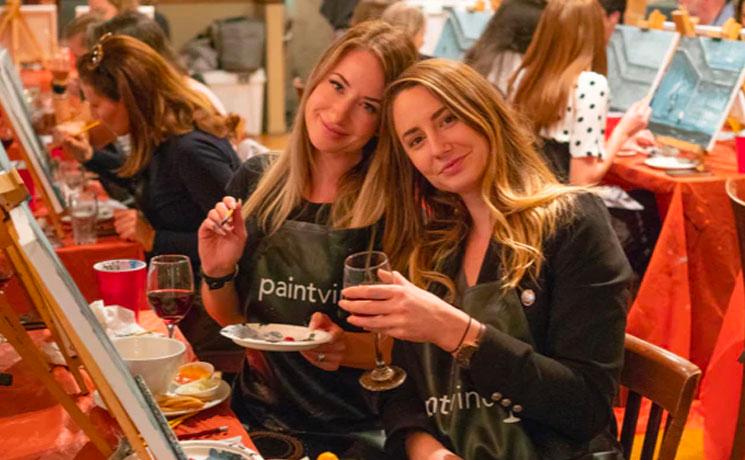 Jeunes femmes peignant avec un verre de vin 