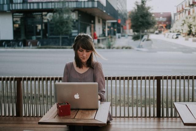 Une jeune femme teletravaille à une terrasse de café au soleil