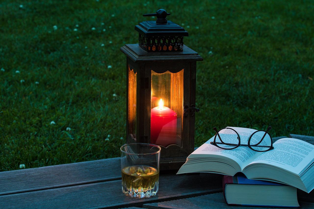 Une lanterne brille sur une petite table près d'un livre 