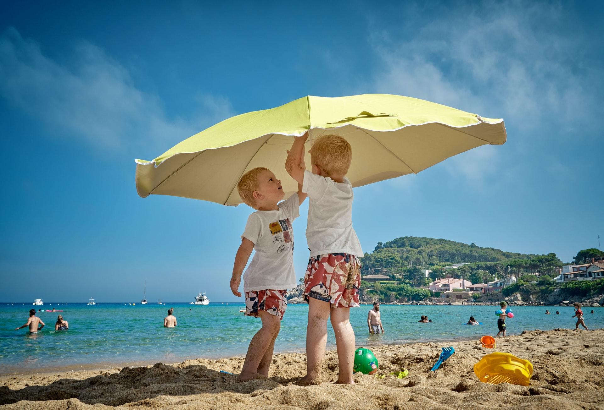 deux enfants sous un parasol jaune a la plage d'alicante