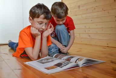 deux enfants sont assis par terre et lisent un livre ensemble 