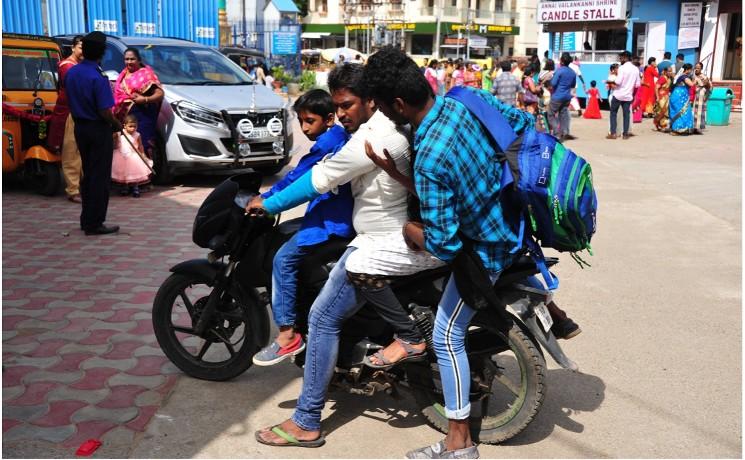 un scooter chargé de 3 personnes dans une rue de Chennai en Inde