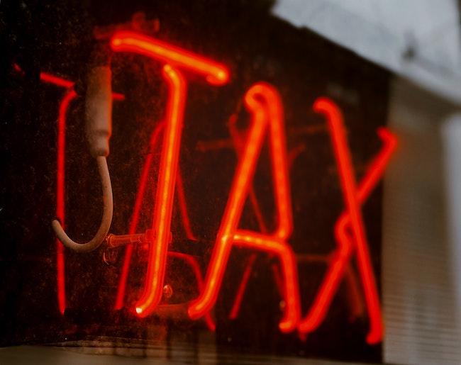 Un néon dans la rue rouge où il est écrit TAX 