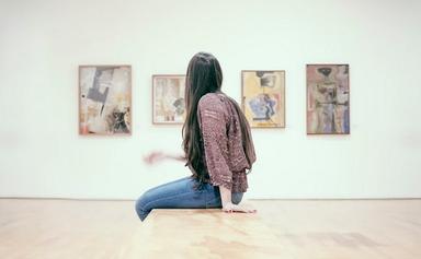 une fille assise observe les tableaux d'une exposition_0