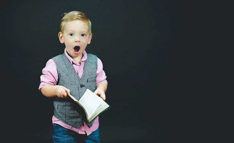 un petit garçon surpris avec un livre