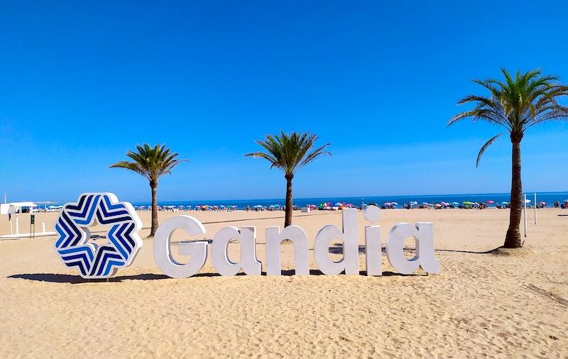 une plage avec trois palmiers et le ciel bleu à Gandia