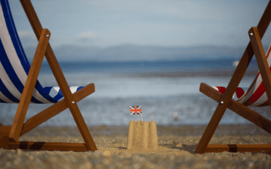 Une plage avec un château de sable et un Union Jack - drapeau du Royaume-Uni - à son sommet pour représenter les jours fériés en 2023