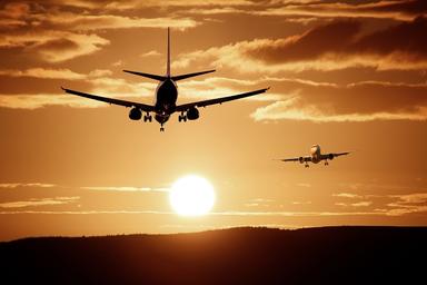 Avions dans le ciel devant un soleil et des nuages orangés