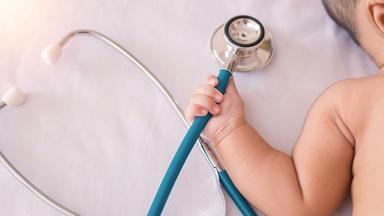 un bebe qui tient un stethoscope  dans sa main