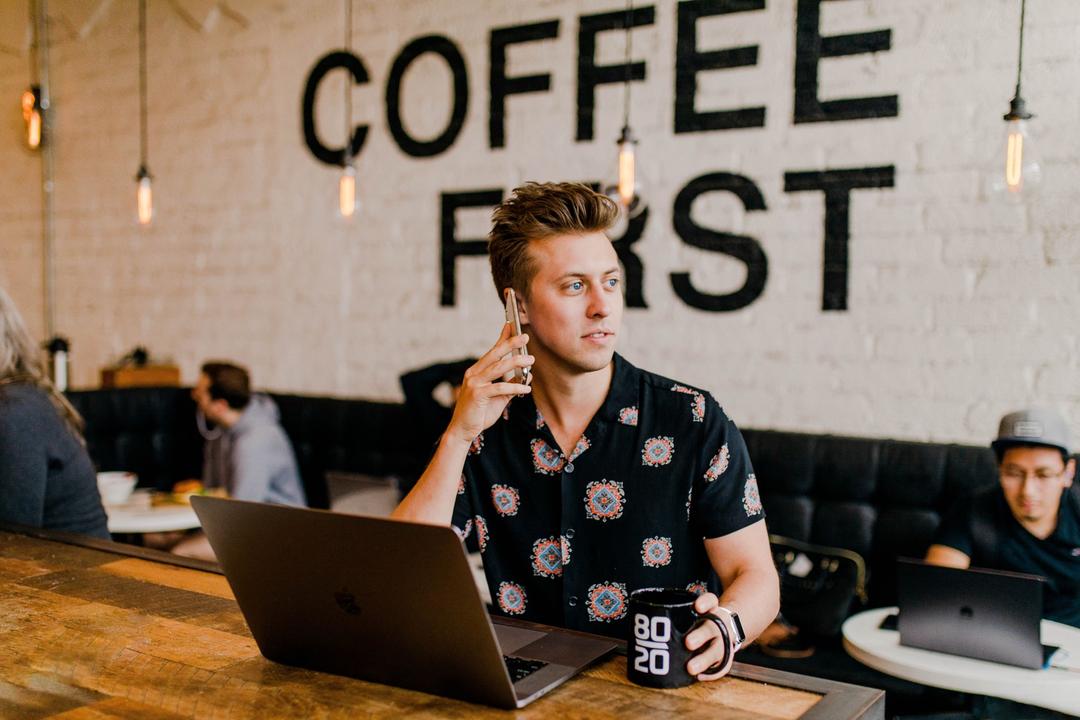 travailler en nouvelle zélande en 2023, un jeune dans un café au téléphone 