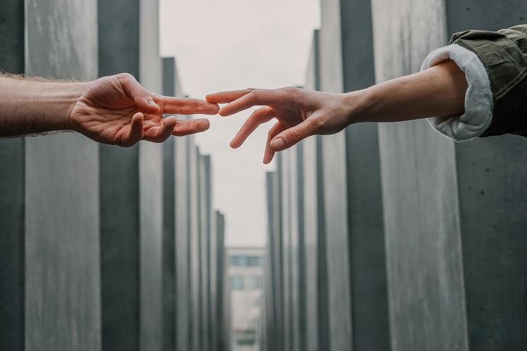 deux mains se touchent à travers un espace frontière