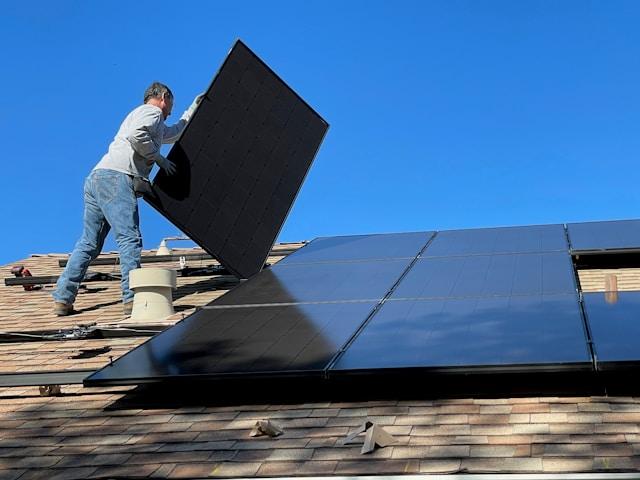 homme posant un panneau solaire