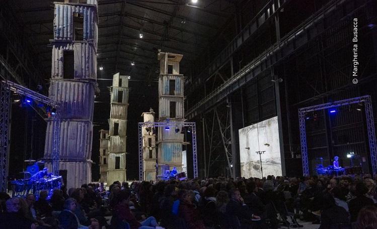 public écoute un concert dans la salle sombre d'un musée