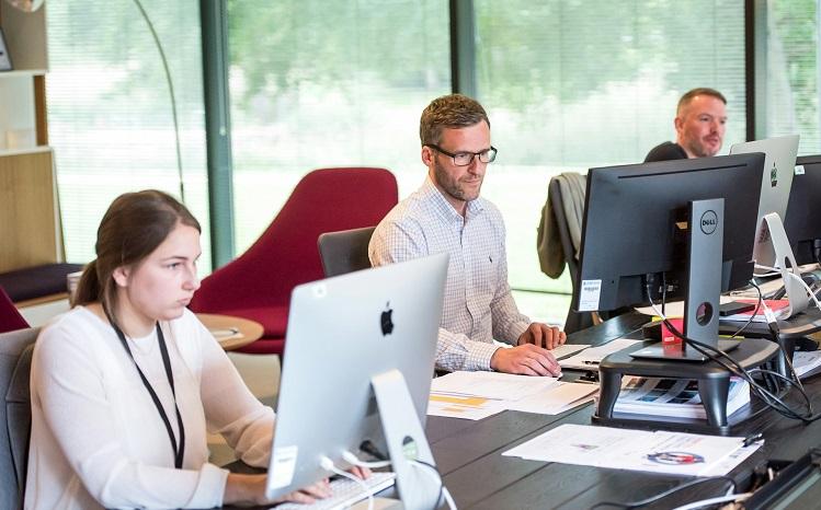 trois personnes travaillent  à leur ordinateur au bureau