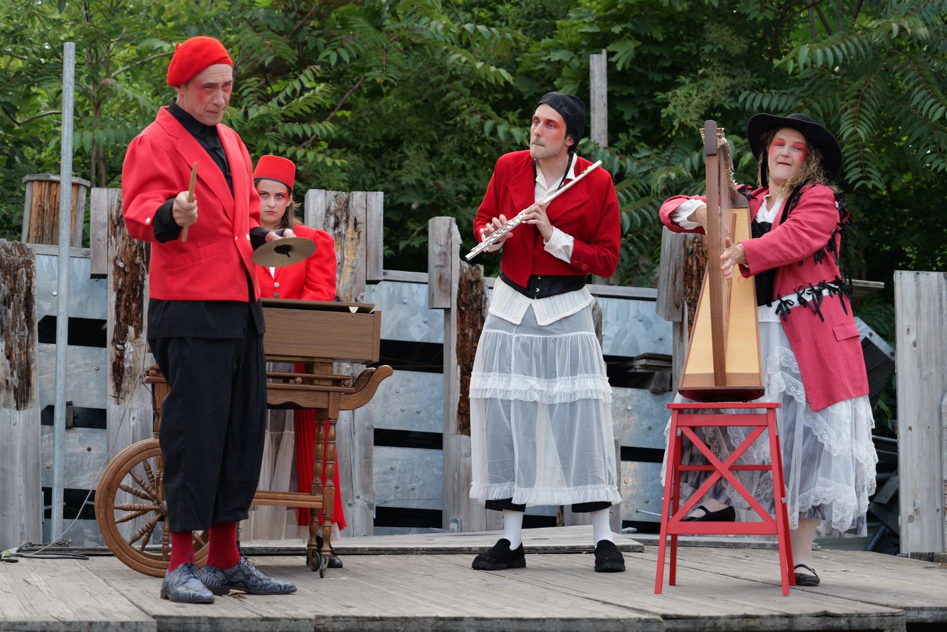 4 personnages sur scène en costume rouges