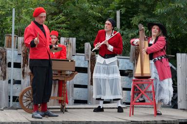 4 personnages sur scène en costume rouges