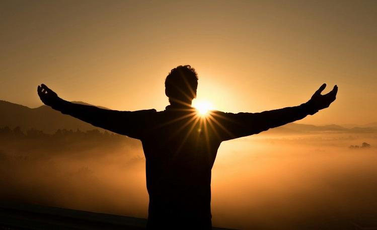 silhouette d'un homme sur la falaise devant le coucher de soleil