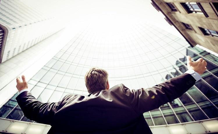 un homme lève les bras en l'air au milieu de bâtiments