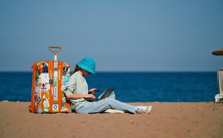 une personne assise sur la plage avec une valise