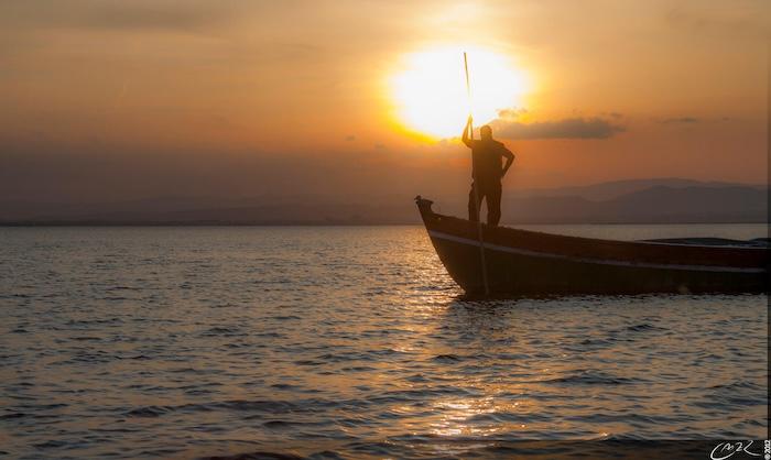 un pecheur sur une barque de l'Albufera au coucher du soleil