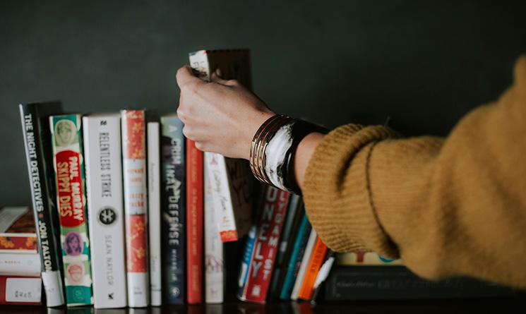 femme qui pioche un livre sur une étagère